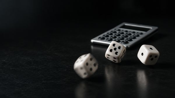 Kolme hopeista noppaa ja prosenttimerkki tummalla taustalla, kertoimet ja todennäköisyys