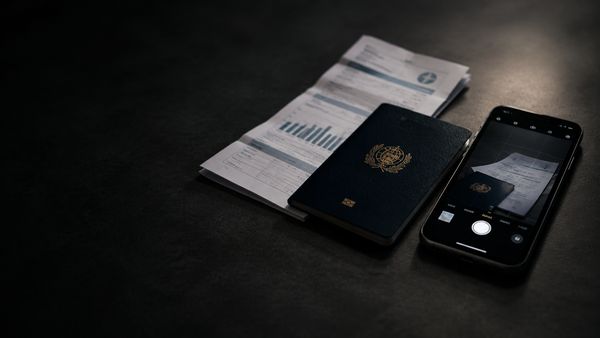 Passi ja taitettu lasku puhelimen vieressä, jonka kamera on auki, tumma pöytä. KYC-tunnistus kasinolla