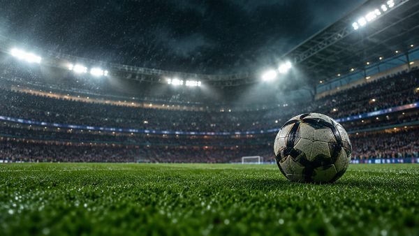 Jalkapallo rehevällä nurmella valtavassa englantilaisessa stadionissa yöllä, täydet katsomot sumeina, valonheittimet ja sadeusva. Valioliiga-vedonlyönti