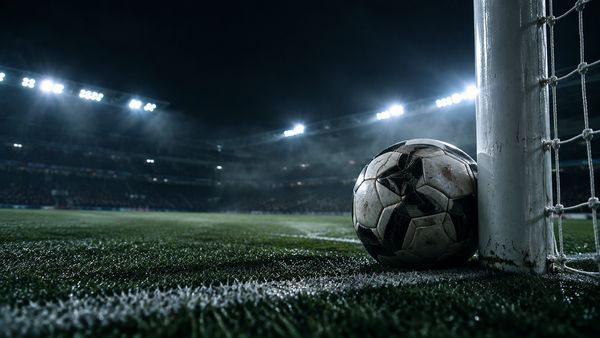Jalkapallo maaliviivalla tolpan vieressä pimeässä stadionissa, valonheittimet, hienoinen usva, matala kuvakulma, over/under
